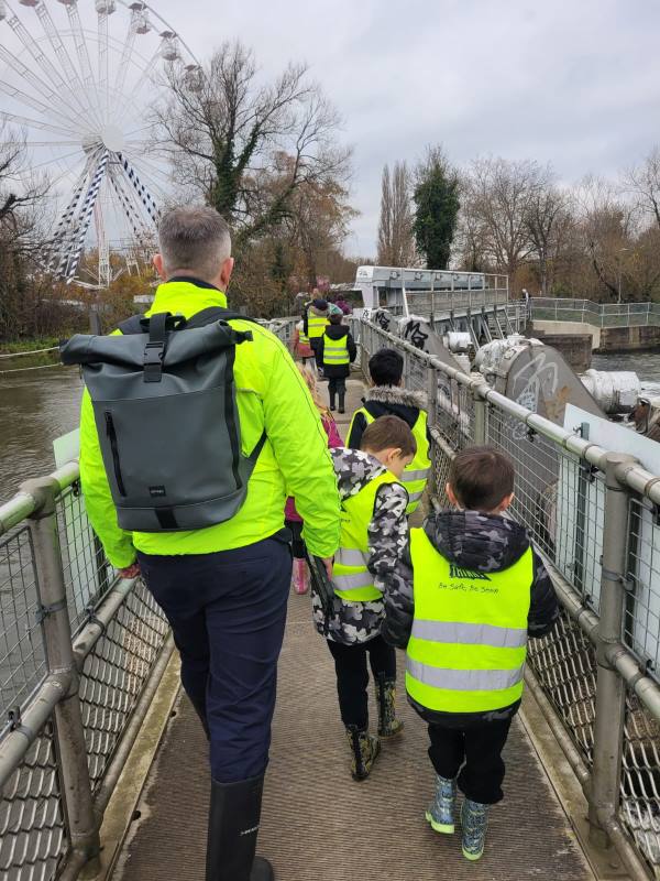 Year 2 children in hi-vis jackets walk across Caversham weir on their trip to Reading Hydro