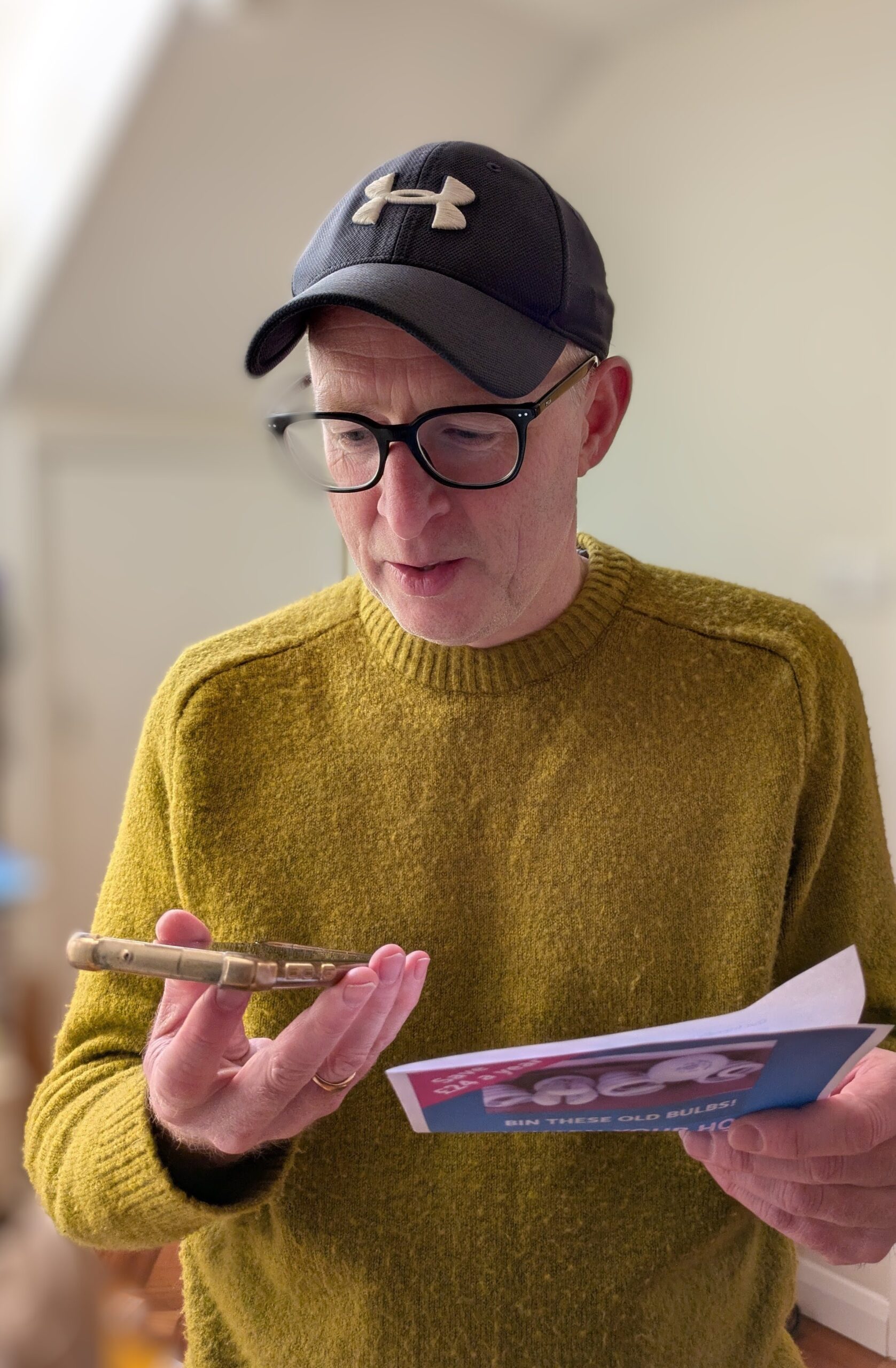 Man holding a smartphone in one hand and a leaflet in the other